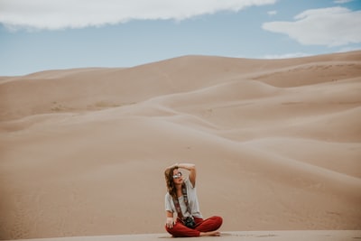 坐在沙漠地面上的女人的极简摄影